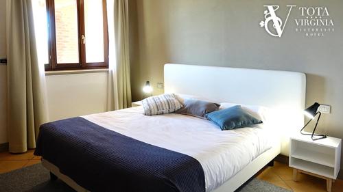 a bedroom with a large white bed with blue pillows at Tota Virginia Antico Podere in Serralunga d'Alba