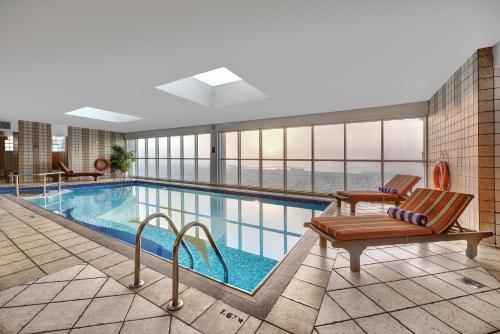 a large swimming pool with two lounge chairs next to it at Emirates Grand Hotel in Dubai