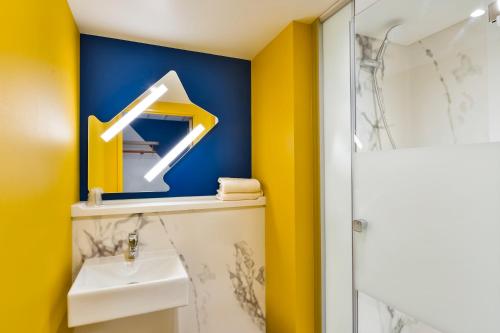 a bathroom with a sink and a blue and yellow wall at ibis budget Geneve Saint Genis Pouilly in Saint-Genis-Pouilly