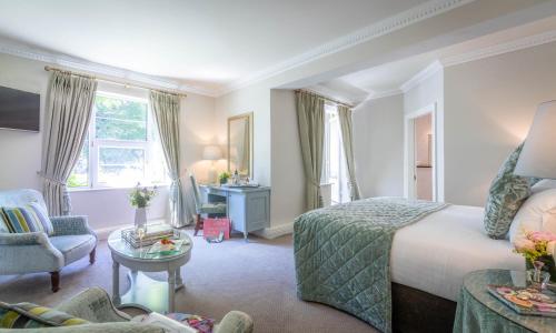 a bedroom with a bed and a chair and a table at Old Ground Hotel in Ennis