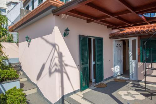 a house with green shutters and a door at Rochinha House in Funchal