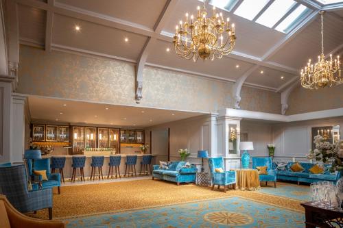 a lobby with blue chairs and a bar at Old Ground Hotel in Ennis
