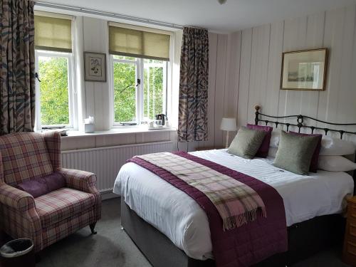 a bedroom with a bed and a chair and windows at The Old Dungeon Ghyll Hotel in Great Langdale