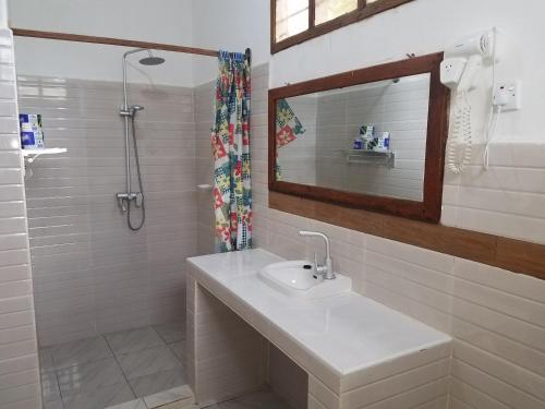 La salle de bains blanche est pourvue d'un lavabo et d'un miroir. dans l'établissement Baraka Beach Bungalows, à Nungwi