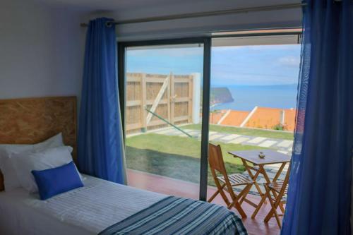 1 dormitorio con cama y vistas a un balcón en HOME4U, en Horta