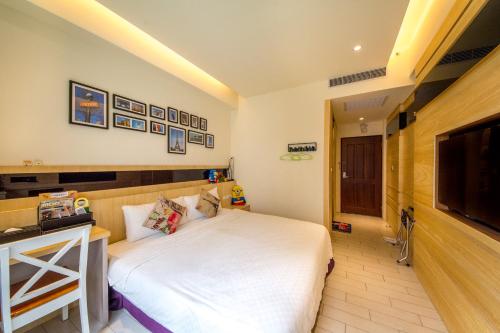 a bedroom with a white bed and a flat screen tv at Zi Jing Cheng B&B in Hualien City