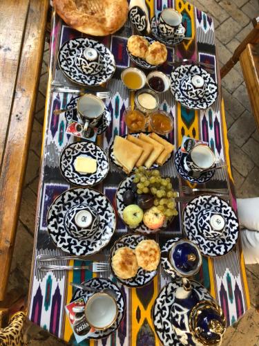 einen Tisch mit Teller mit Lebensmitteln auf einem Tisch in der Unterkunft Hotel Legende in Samarkand