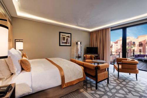 a bedroom with a large bed and a living room at Mövenpick Hotel Mansour Eddahbi Marrakech in Marrakech