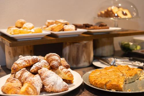 a bunch of pastries on plates on a table at Hotel Weiher Green Lake in Falzes