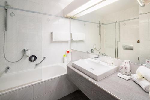 a white bathroom with a sink and a bath tub at Best Western Plus Parkhotel Erding in Erding