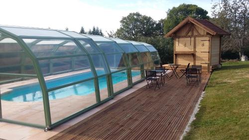 une terrasse en bois avec une maison et une piscine dans l'établissement domaine de la louvière, à Le Clerjus