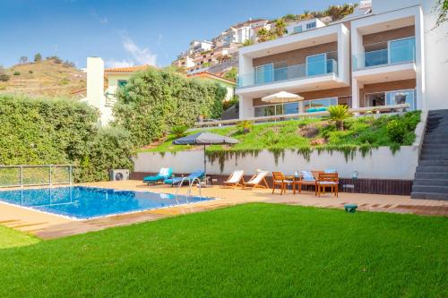 a backyard with a swimming pool and a house at Villa Chimera By LovelyStay in Caniço