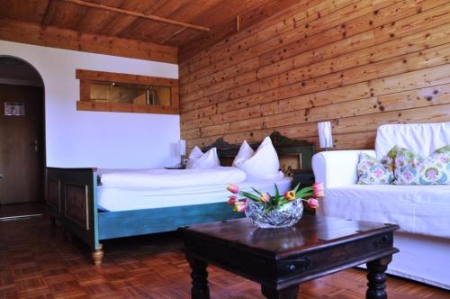 a room with two beds and a table and a couch at Pension Hirsch in Lechbruck