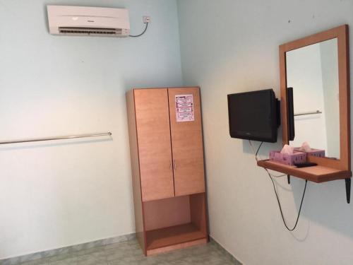a room with a cabinet and a television and a mirror at Rose Inn Motel in Kuah