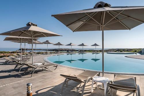 a swimming pool with chairs and umbrellas at Kavos Hotel & Suites in Stavros