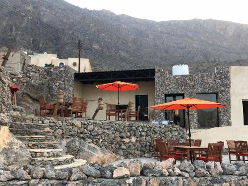 a restaurant with tables and umbrellas on a stone wall at SAMA Wakan Heritage Homes in Fanjah