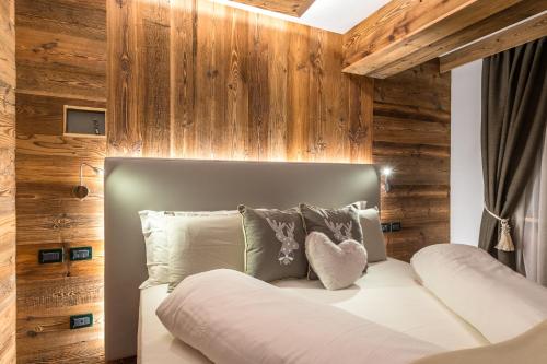 a bed in a room with wooden walls at Alpstyle Hotel Albolina Wellness & Beauty in Canazei