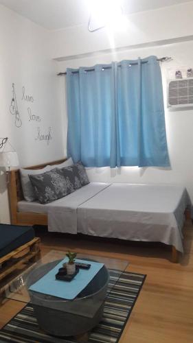 a bedroom with a bed with blue curtains and a table at The Treehouse B @ Trees Residences in Manila