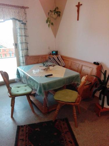 a room with a table and chairs and a cross on the wall at Ferienwohnung Dichtl in Grafenau