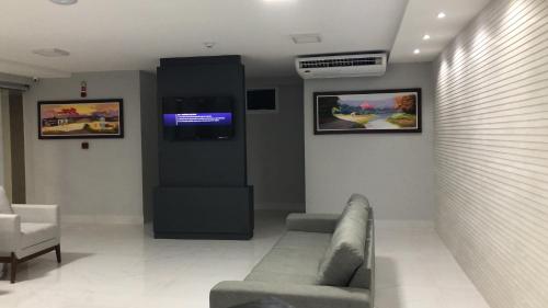 une salle d'attente avec un canapé et une télévision dans l'établissement Hotel Oásis de Patos, à Patos