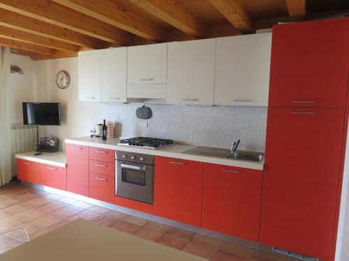 een rode keuken met witte kasten en een wastafel bij Maisonette Caterina in Tremosine Sul Garda
