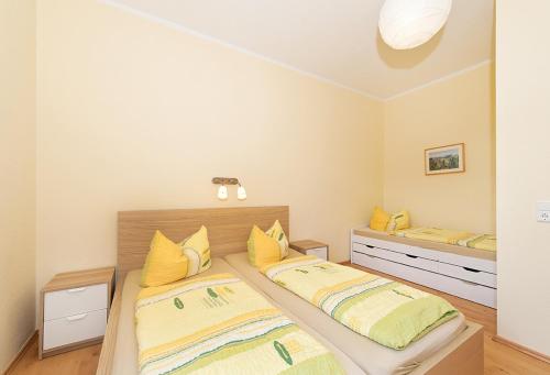 two beds in a bedroom with yellow pillows at Panorama-Apartments Weinberghaus in Mittelndorf