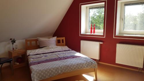 - une chambre avec un lit dans une chambre rouge dotée de 2 fenêtres dans l'établissement Ferienhaus Hildegard, à Muhr amSee