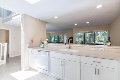 uma cozinha com armários brancos, um lavatório e duas janelas em Coral Reef Resort em Hilton Head Island