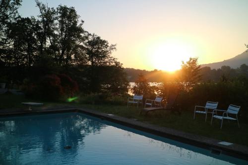 a swimming pool with chairs and the sunset in the background at Lake Villa Lotus in Luzern