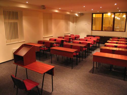 a classroom with red desks and chairs in a room at Dinaburg SPA Hotel in Daugavpils