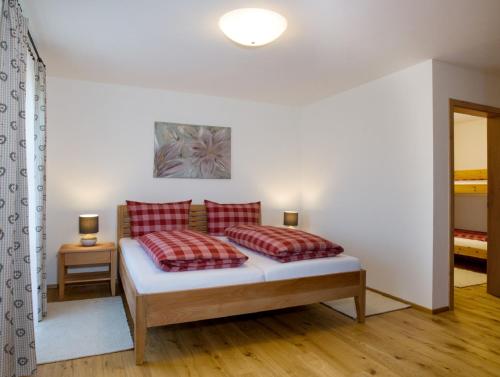 a bedroom with a bed with two red pillows at Ferienhof "Schoppa-Haisl" in Sonnen