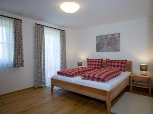a bedroom with a bed with two red pillows at Ferienhof "Schoppa-Haisl" in Sonnen