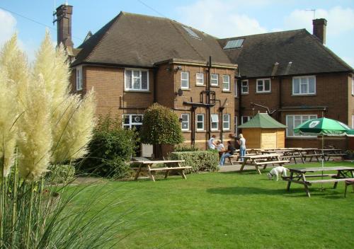 a building with picnic tables in front of a building at Bird In Hand in Henlow