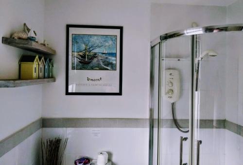 a bathroom with a shower and a picture on the wall at Summerwind Guest House in Exmouth
