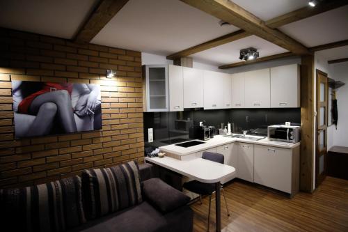 eine Küche mit weißen Schränken und einer Ziegelwand in der Unterkunft Apartamenty Wygoda Białystok in Białystok