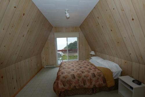1 dormitorio con 1 cama en una habitación con paredes de madera en Chalets Anse à Jos/Yves, en Les Escoumins