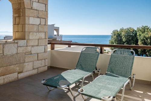 a pair of chairs on a balcony with the ocean at Kavos Hotel & Suites in Stavros