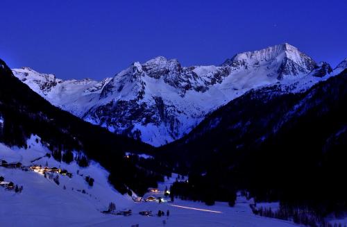 a snow covered mountain range at night with a village in the snow at Bergchalet Hotel Reinerhof in Riva di Tures