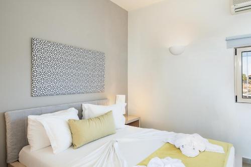 a bedroom with a white bed with white pillows at Kavos Hotel & Suites in Stavros