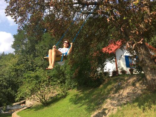 a woman sitting on a swing in a tree at Domek na Podlasiu in Mielnik