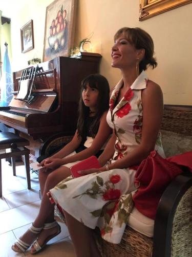 two women sitting on a chair in front of a piano at Bergchalet Hotel Reinerhof in Riva di Tures