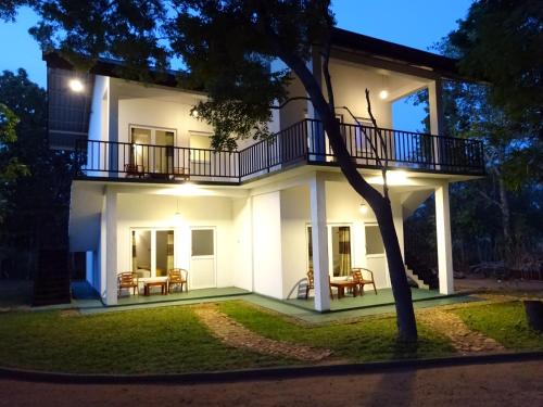 uma grande casa branca com uma varanda à noite em Kadulla Resort em Habarana