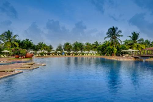 a pool at a resort with palm trees in the background at The LaLiT Golf & Spa Resort Goa in Canacona