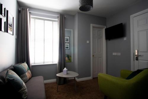 a living room with a couch and a table and a window at Wilde Ballybunion in Ballybunion