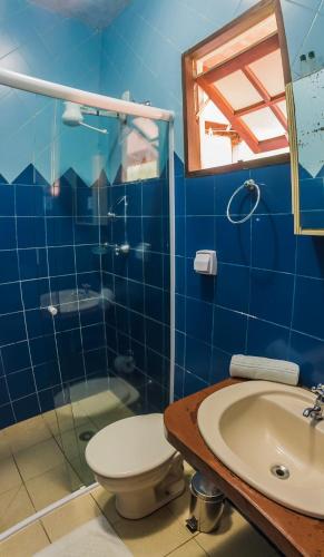 a blue bathroom with a toilet and a sink at Pousada Tubes Maresias in Maresias