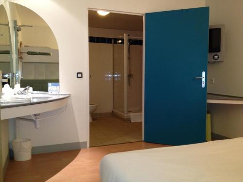 La salle de bains est pourvue d'une porte bleue menant à un lavabo. dans l'établissement ibis Budget Caen Centre Gare, à Caen