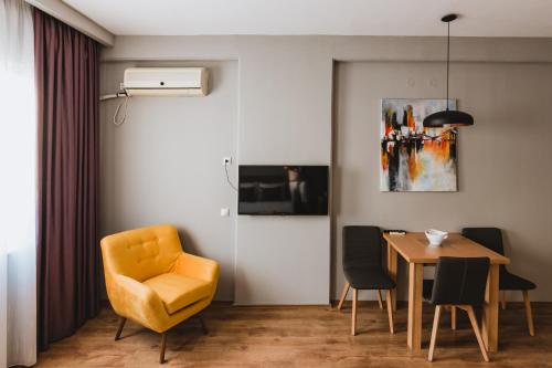 a dining room with a yellow chair and a table at Central Plaza Apartments in Niš