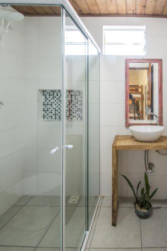 a bathroom with a glass shower and a sink at Morada Amazona in Praia do Rosa