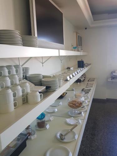 a kitchen with white plates and dishes on shelves at Flat Saint Paul Residence in Bauru