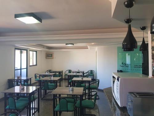 a dining room with tables and green chairs at Flat Saint Paul Residence in Bauru